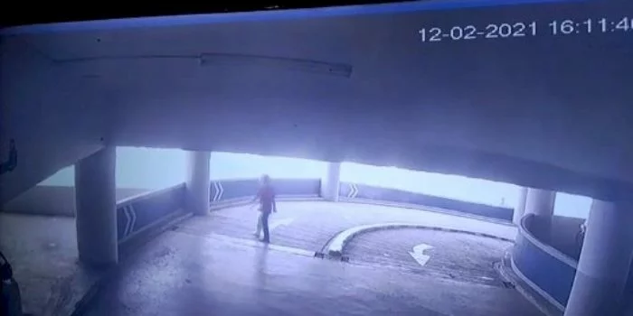 Tangkap layar rekaman CCTV yang menunjukkan seorang pria mengitari parkiran mobil sebelum terjun bebas/Repro